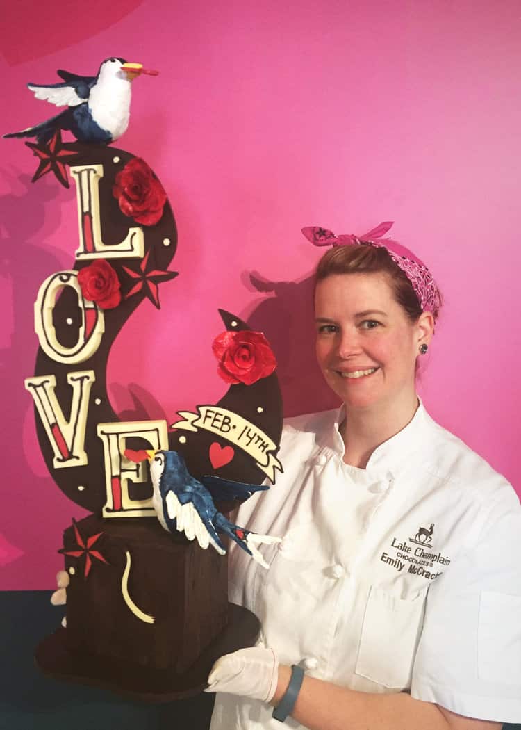 Emily McCracken holding her valentine's day chocolate sculpture in front of a pink wall